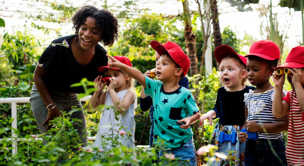 image showing teacher and children who are looking at plants with amazement